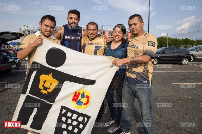 Fans de los Pumas posan con un cartel en contra de las Águilas