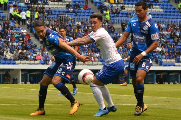 Rodríguez  disputa un balón con dos jugadores de Puebla