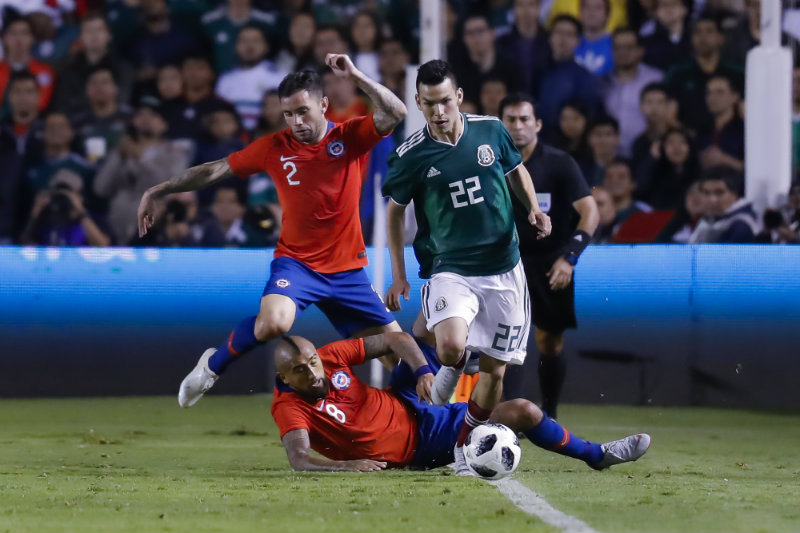 Lozano disputa un balón con Arturo Vidal 