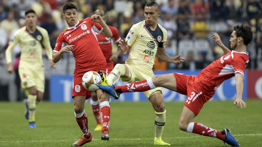 Paul Aguilar pelea por el balón contra dos defensas del Toluca 