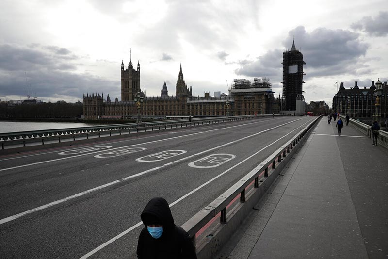 Una persona con mascarilla camina por el puente de Westminster