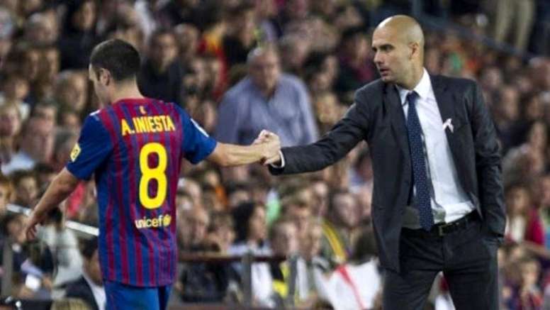 Guardiola saluda a Iniesta en un juego del Barcelona
