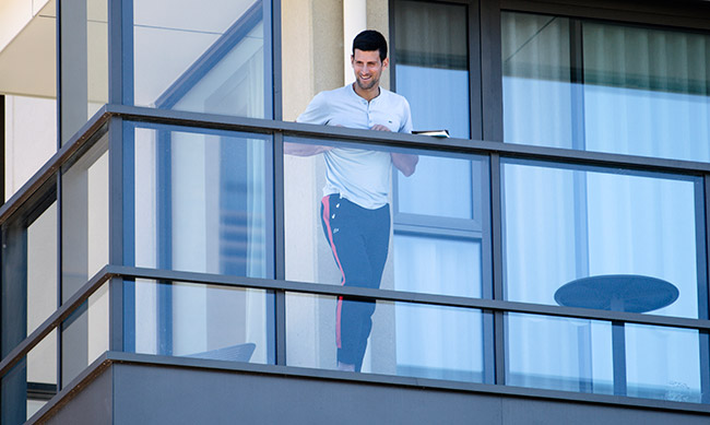 Djokovic, otro tenista resguardado, se asoma desde su balcón de hotel