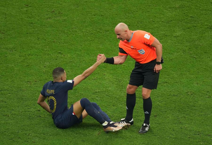 Szymon Marciniak ayudando a Kylian Mbappé tras una jugada de Messi