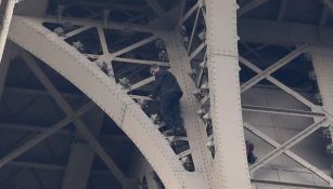 Hombre intentando escalar la torre Eiffel 