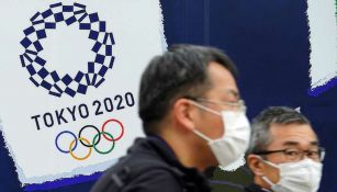 Ciudadanos de Tokio caminan frente a un cartel de los Juegos Olímpicos
