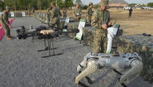 Un hombre del ejército chino, a la derecha, prueba una ametralladora equipada con un perro robot antes de participar en ejercicio militar