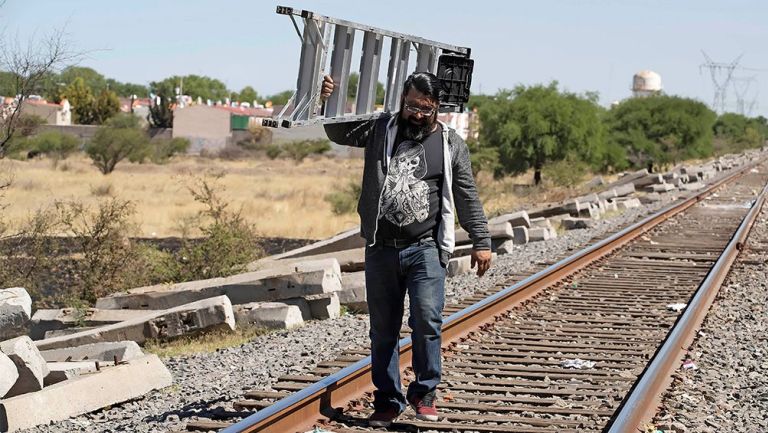 Aficionado del América camina por las vías del tren con una escalera