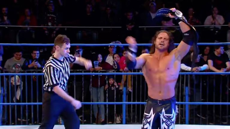 Johnny Impact festeja con el título en el centro del ring